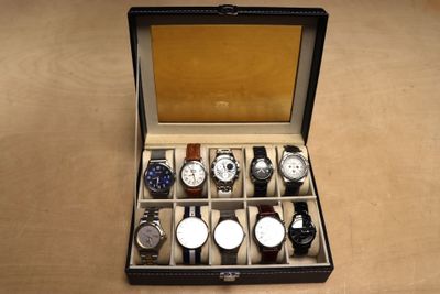plusieurs montres dans un coffret posé sur une table au plateau en bois