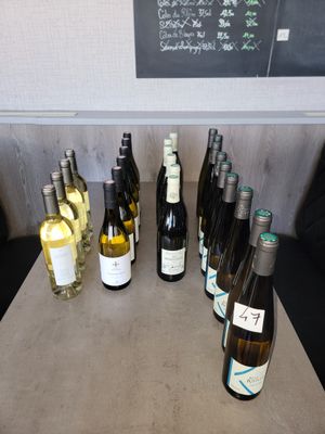 Des bouteilles de vin sont alignées sur une table devant un tableau noir.