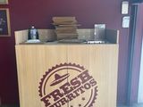 a wooden counter with a sign on it in front of a red wall