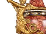 a gold and red vase with two statues on it
