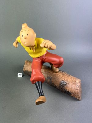 figurine of a man sitting on a log on a gray surface