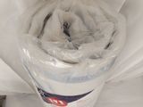 un rouleau de papier toilette emballé dans du plastique, posé sur un lit