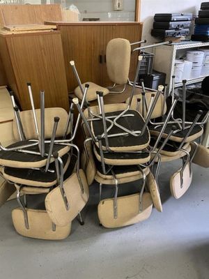 de nombreuses chaises, empilées les unes sur les autres dans une pièce