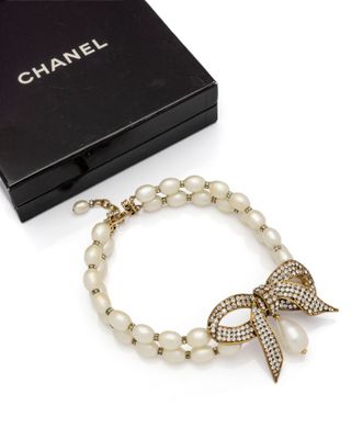 a close up of a bracelet with pearls and a bow