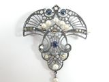 une image représentant une broche ornée de perles et de pierres précieuses sur fond blanc