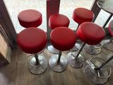 several red stools sit in front of a glass door in a restaurant