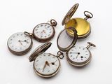 plusieurs montres de poche anciennes empilées les unes sur les autres sur une surface blanche