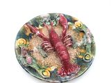 une assiette sur laquelle est posé un homard rouge, posée sur une table blanche
