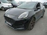 La voiture noire est garée sur un parking, avec d'autres voitures en arrière-plan.