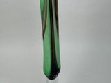 a green glass vase with a black base on a white table