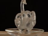 a glass bird sitting on a glass plate on a table