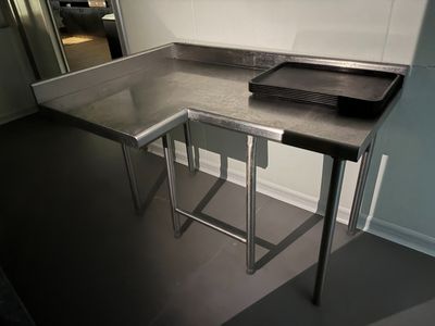 une table en acier inoxydable sur laquelle est posé un plateau