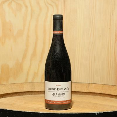 a bottle of wine sitting on top of a barrel