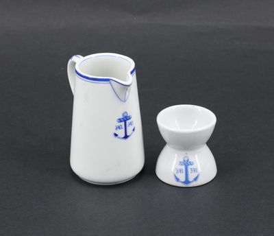 a white and blue pitcher and a small cup on a black surface