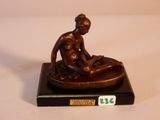 statue représentant une femme assise sur les genoux d'un homme, posée sur un socle en marbre