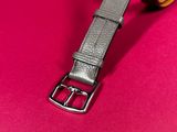 a close up of a leather belt on a pink surface