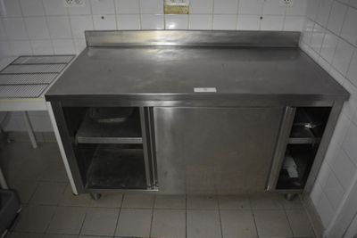 un plan de travail en acier inoxydable dans une cuisine carrelée de blanc