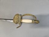 a picture of a sword with a gold handle on a gray surface