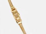 gros plan d'une montre-bracelet en or sur une surface blanche