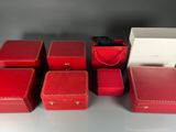 six boîtes rouges munies de poignées sont disposées sur une table