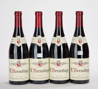 quatre bouteilles de vin rouge sont alignées sur une table