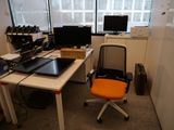 un bureau avec un ordinateur portable, un écran et une chaise, placé devant une fenêtre