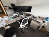 un bureau d'ordinateur avec deux écrans et une chaise dans un coin