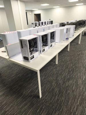 many computers sitting on a table in a room