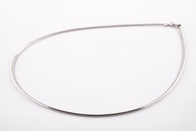 gros plan d'un collier en argent sur une surface blanche