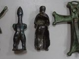 three bronze figurines of people and a cross on a white surface