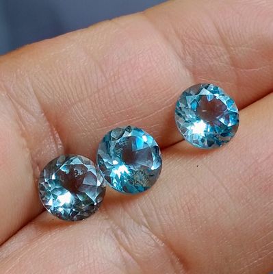 deux pierres de topaze bleue sont posées sur la main d'une personne