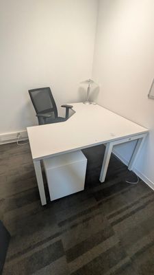 a white desk with a black chair in the corner