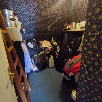 a room with a ladder and a closet with clothes on it