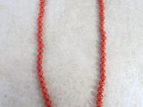 a close up of a red beaded necklace on a white surface