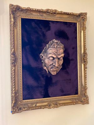 a painting of a man ' s face hanging on a wall