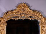 a mirror with a gold frame on a white wall