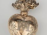 une image représentant une broche en or en forme de cœur ornée d'une croix