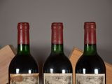 two bottles of red wine sitting next to each other on a table