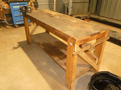 un établi en bois dans un garage, avec un seau posé par terre