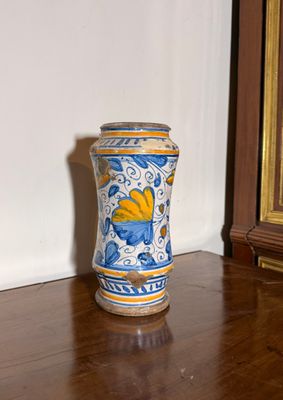 un vase bleu et jaune posé sur un parquet