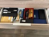 a desk with a drawer that has various items in it