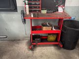 un établi rouge sur lequel sont posés des outils, à côté d'une poubelle