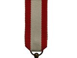 une vieille médaille ornée d'un ruban rouge et blanc sur fond blanc