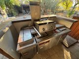 an outdoor kitchen with a grill and sink in it