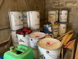 many buckets of paint sitting on a pallet in a room