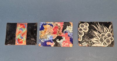 trois petites œuvres d'art sont posées sur une surface bleue