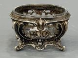 an antique silver plated bowl on a stand on a gray surface