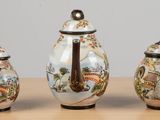 three small vases sitting on a table with a bird on them