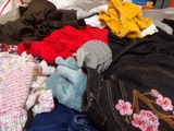 a pile of clothes on a bed with a stuffed animal