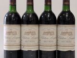 quatre bouteilles de vin sont alignées sur une surface blanche